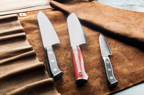 Japanese knives of different sizes from Damascus steel are in a leather case. Business concept of career growth
