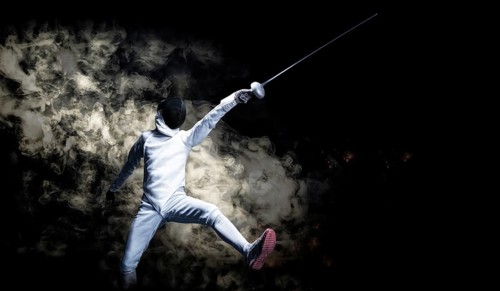 The fencer moves forward with a sword in his hand. Sport concept.
