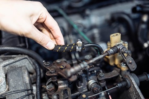 Auto mechanic regulates fuel supply with throttle cable lever