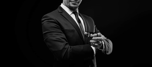 Image of an adult stylish man in a suit with a cigar. Cigar clubs concept.