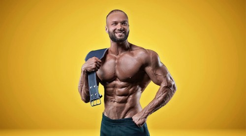 Isolated professional sportsman on a yellow background. Bodybuilding concept. Panorama. Advertising of a gym and sports nutrition.
