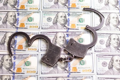 Handcuffs on the background of hundred-dollar bills. Illegal trade. Justice concept.