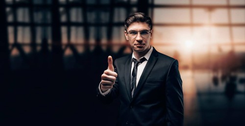 Portrait of a man in a business suit. He is standing at the airport with his finger raised. Ok sign. VIP transportation. Private airlines. Charter flights.