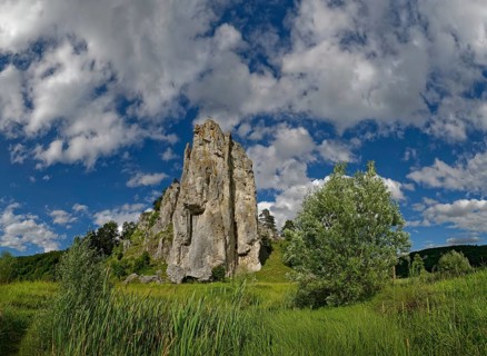 Striking limestone rock formation Burgstein with blue and white sky in the upper Altmuehltal surrounded by green vegetation