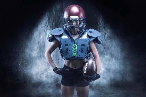 Brutal portrait of a girl in the uniform of an American football team player. Equipment advertising. Sports concept. Shoulder pads.