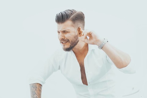 Stylish man in a shirt listens to explanations by turning his ear to the guilty employee. The concept of irresponsibility