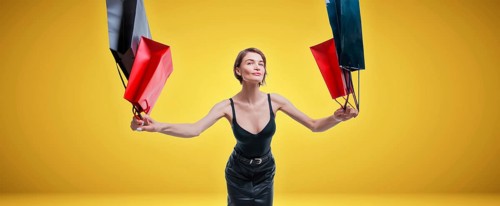 Cheerful positive girl jumps up with happiness and waving shopping bags. The concept of holiday gifts