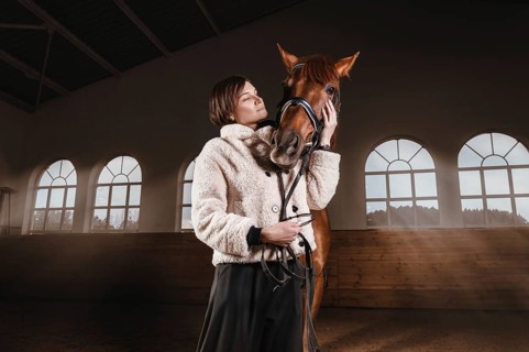 Portrait of a stylish woman hugging a thoroughbred horse. Love and care concept.