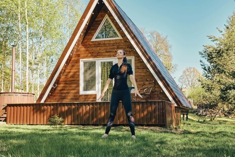 Sporty woman does breathing exercise on lawn of her country house