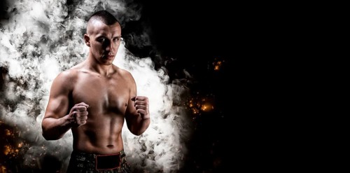 Portrait of a boxer of mixed martial arts standing on the background of smoke and fire. The concept of sports