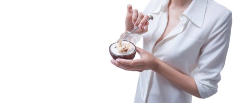 Woman posing in studio with natural coconuts in which dessert is served. Organic food.