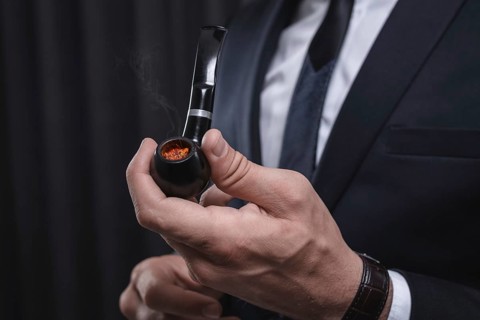 Image of male hands holding a smoking pipe. Tobacco smoking concept.