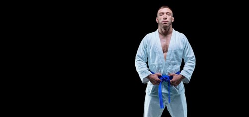 Professional athlete stands in the gym in a kimono with a blue belt. Concept of karate