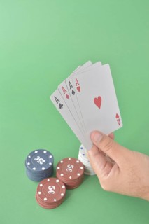 Four aces fan out in a hand above stacked poker chips on a green surface