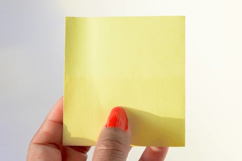 Woman's hand with painted nails holding blank letter paper on pure white background