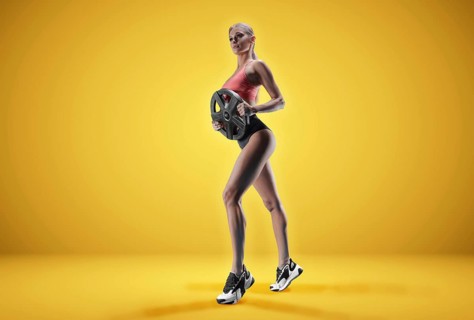 Delightful athlete posing in the studio with weights in her hands. The concept of sports