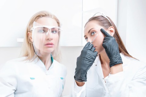 Portrait of the beautician and patient. The doctor injects botox. Skin rejuvenation and lifting concept.