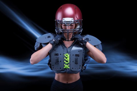 Brutal portrait of a girl in the uniform of an American football team player. Equipment advertising. Sports concept. Shoulder pads.