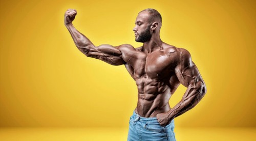 Isolated professional sportsman on a yellow background. Bodybuilding concept. Panorama. Advertising of a gym and sports nutrition.