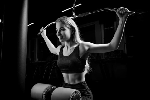 Charming blonde does exercises for the back in the gym. Neck pull for the head. The concept of sports