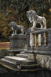 Two lion statues on a stone staircase leading to a small pond