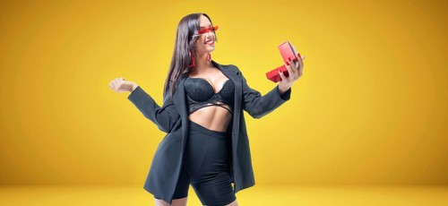 Sexy tall brunette in lingerie admires jewelry. Yellow background. The concept of gifts and congratulations.