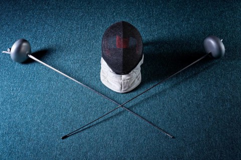 Two swords and mask lie on a blue background. The concept of fencing.