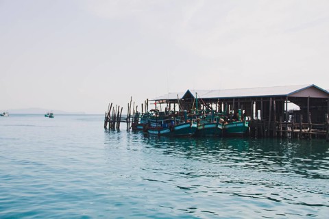 Fishing boats moored at a wooden pier in a serene waterfront village. Koh Sdach Island