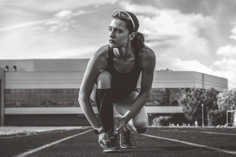 Image of an athlete tying her shoelaces with spikes. Running concept.
