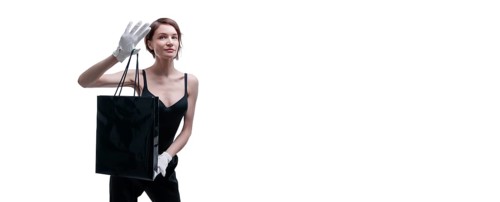 Stylish tall girl in white gloves demonstrates a black luxury package. The concept of safe shopping during a pandemic