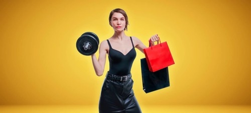 Beautiful slender woman posing in the studio with a dumbbell and gift bags. Gift concept. Gym membership