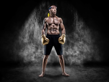 Professional wrestler is standing in the smoke in a dark place. Mixed martial arts