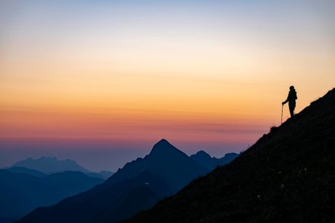 Mountaineer on mountain ridge with Rothorn peak in the background at blue hour