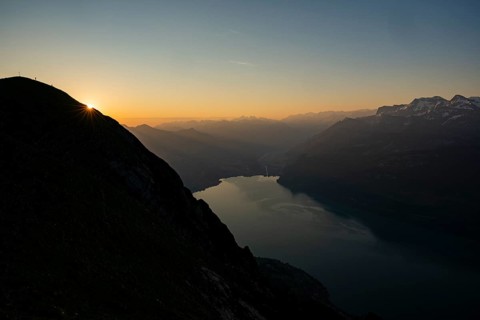 Mountain ridge with mountaineers and Swiss mountains and Lake Thun in the background at sunrise