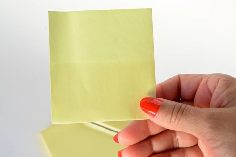Woman's hand with painted nails holding blank letter paper on pure white background