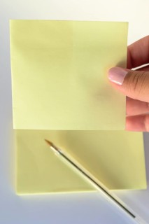 Woman's hand with painted nails holding blank letter paper on pure white background