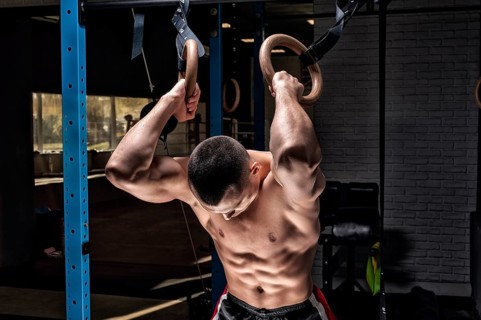 Athlete does warm-up on gymnastic rings. The concept of sport and healthy lifestyle.