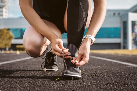 Image of an athlete tying her shoelaces with spikes. Running concept.