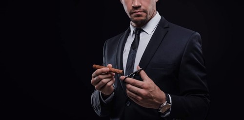 Image of an adult stylish man in a suit with a cigar. Cigar clubs concept.