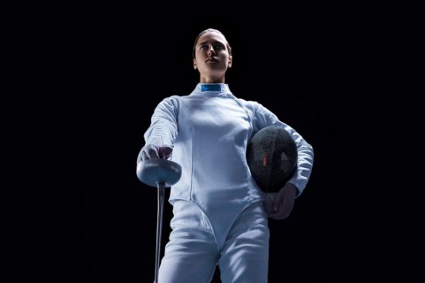Charming girl dressed as a fencer posing with a mask and a sword. The concept of fencing.