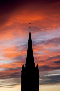 Silhouette of the late Gothic church tower of Radolfzell Minster against a dramatic orange and red sky at sunrise