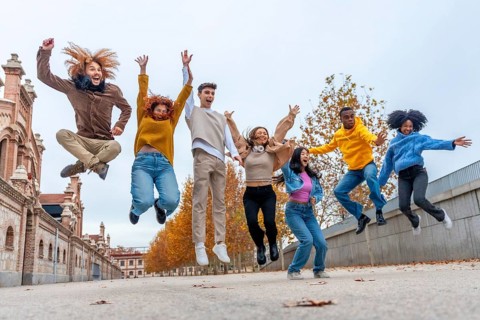 Happy multi-ethnic friends jumping in the street in an autumn day