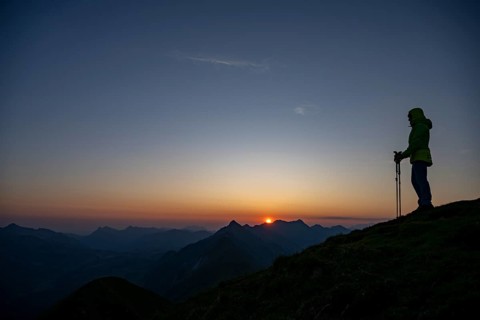 Mountaineer on mountain ridge with Rothorn peak in the background at sunrise