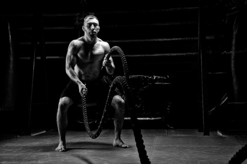 The athlete works with crossfit ropes in the gym. The concept of sports