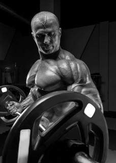 Professional weightlifter posing in the gym with a barbell in his hands. Classic bodybuilding.
