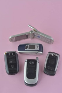 A birds-eye view of classic flip phones on a plain pink background