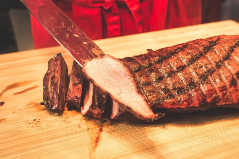 A piece of meat is sliced after grilling