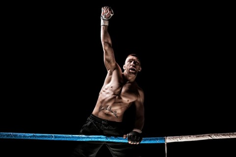 Kickboxer posing in the ring. The athlete climbed the ropes and took a winning pose. The concept of mma