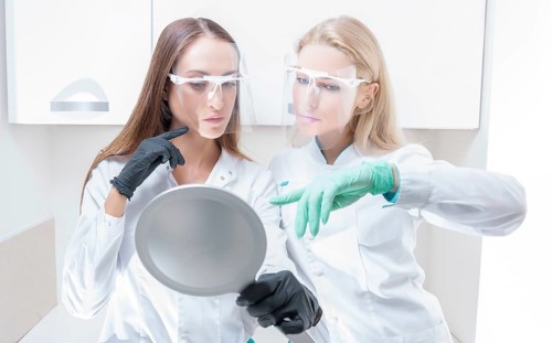 Two beauticians pose in a medical salon with a mirror in their hands. Rejuvenation concept.