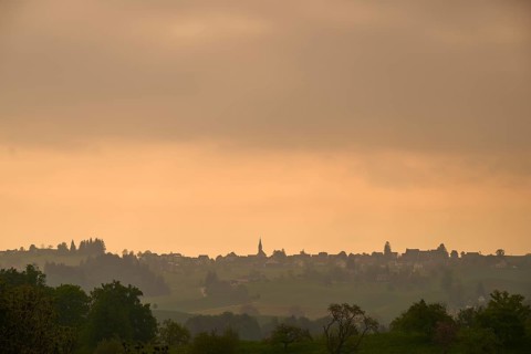 Silhouette of a village on a hill under an orange-coloured sky at sunrise
